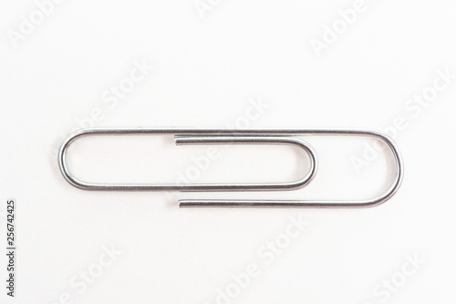 A horizontal macro shot of a common paper clip set on a white background. © Dominique James