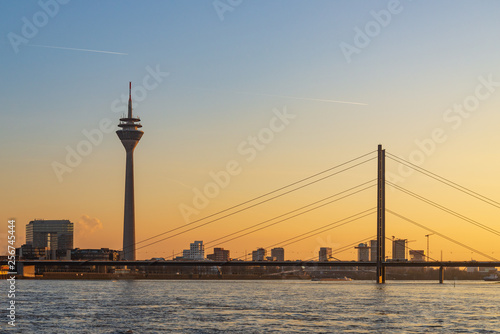 Outdoor scenery of Düsseldorf City skyline, downtown, tower bridge, riverside and Rhine River, and beautiful background of gradient sunset sky.  © Peeradontax