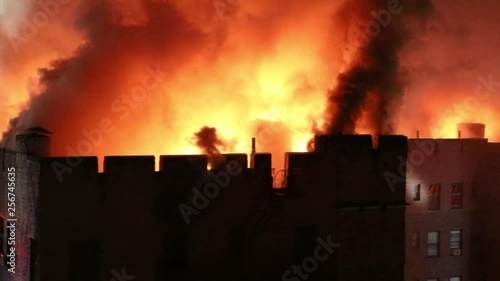 Firehoses Spraying Water onto a Roof Fire on a Six Story Apartment Building at Night, Close Up