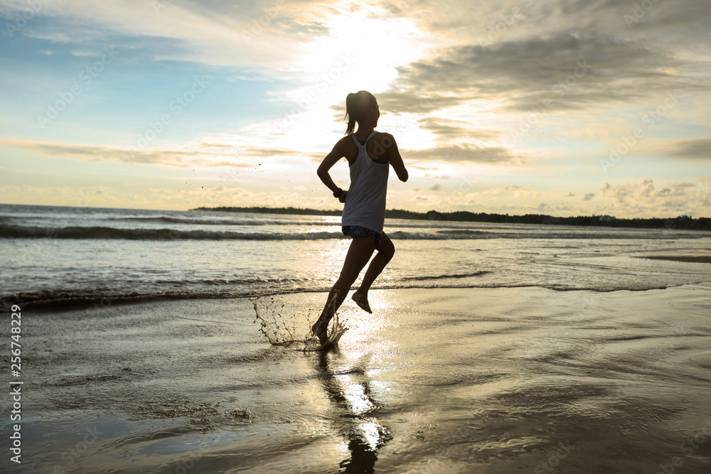 young fitness woman running at sunset beach