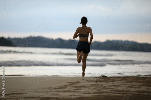 Female athlete running at sunset on beach