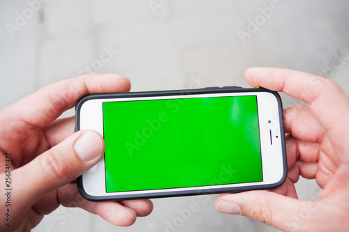 Fototapeta Naklejka Na Ścianę i Meble -  Personal perspective of a man using a smartphone with a green screen