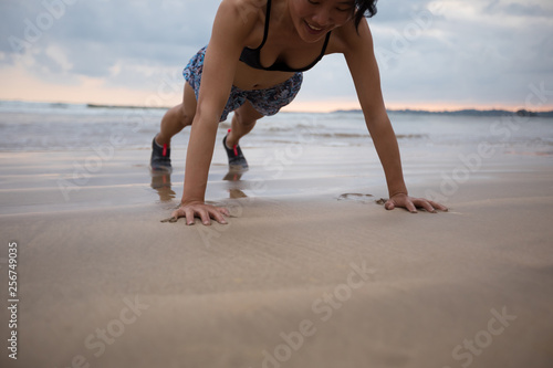 Fitness asian woman doing pushups at sunset seaside  healthy lifestyle concept.