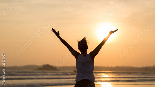 Woman open arms on sunset beach Rear View