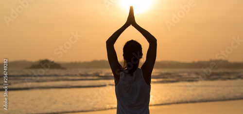 Woman pracice yoga on sunset beach Rear View photo