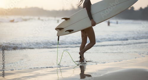 Surfer woman walking with surfboard on the beach 