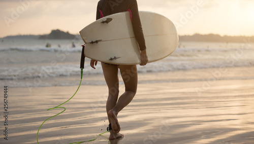 Surfer woman walking with surfboard on the beach 