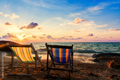 Summer vacation deckchairs on tropical beach and ocean sea with sunrise background. Travel and vacation background.