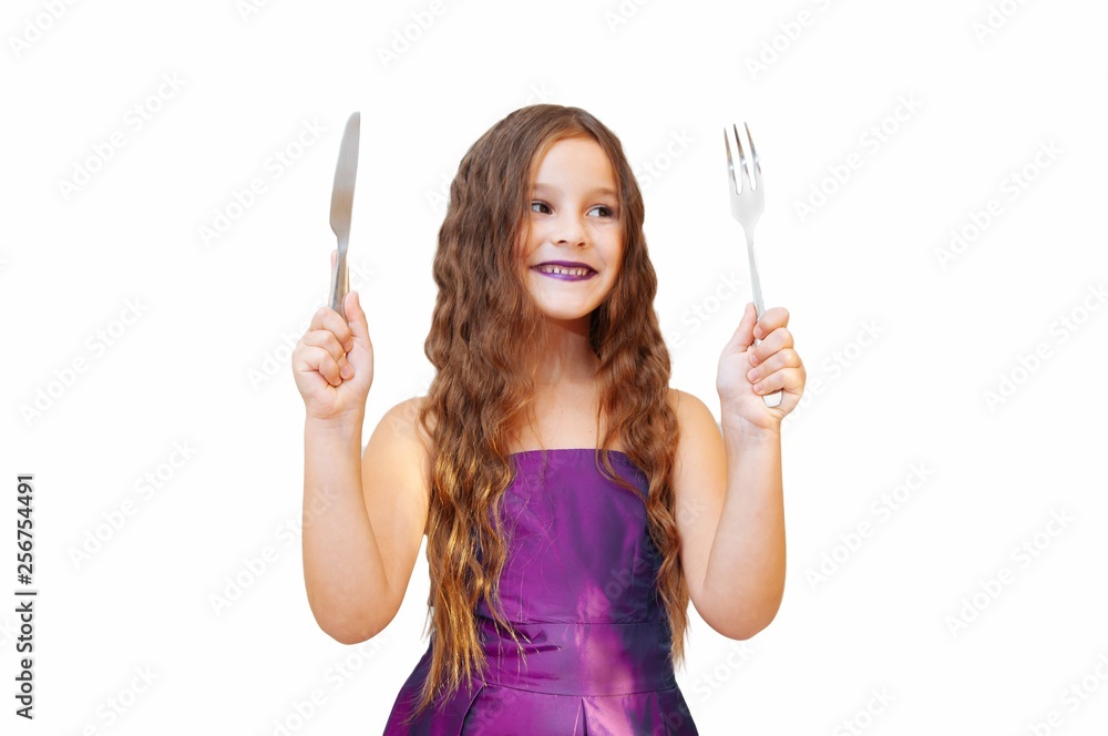 Beautiful little girl with long hair in evening dress, portrait emotionally posing with a knife and fork, isolated Beautiful little girl with long hair in evening dress, portrait emotionally posing with a knife and fork, isolated