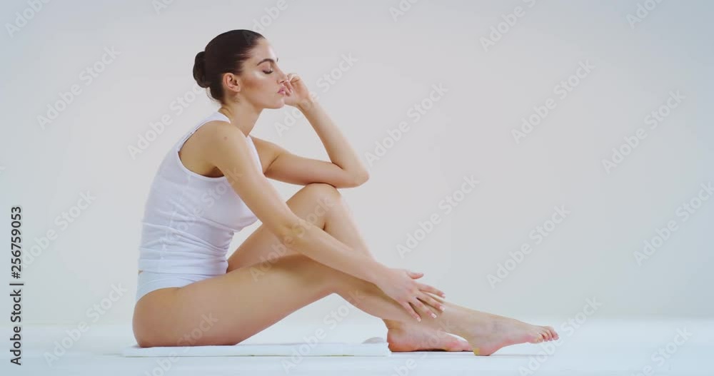 Slow motion of young beautiful woman with perfect body touching gently her hairless soft and silky legs after depilation isolated on a white background. Slow motion of young beautiful woman with perfect body touching gently her hairless soft and silky legs after depilation isolated on a white background.