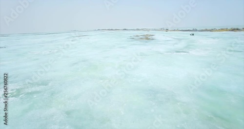 Flying above wonderfully blue ice fo frozen lake Hanka in Russia, white swamp buggy is driving on ice on the background photo