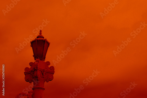 Retro street lamp shining at night against cloudy sky. old street lamp on red sky  couds background