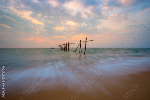 The old and broken wooden bridge on the beach with sunset