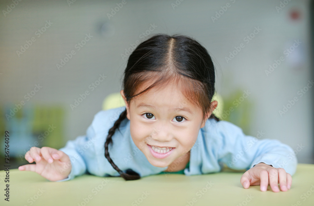 Adorable little Asian girl laying on children table with smiling and looking at camera, Happy kids. Adorable little Asian girl laying on children table with smiling and looking at camera, Happy kids.