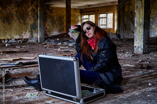 Girl in a black cloak with a diplomat and money in a ruined room. A spy in a secret meeting. Unusual photo shoot photo