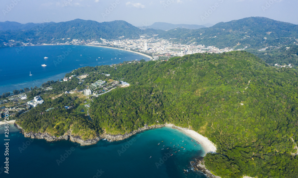 View from above, stunning aerial view of Patong city skyline in the distance and the beautiful Freedom Beach bathed by a turquoise and clear sea in the foreground, Phuket, Thailand.