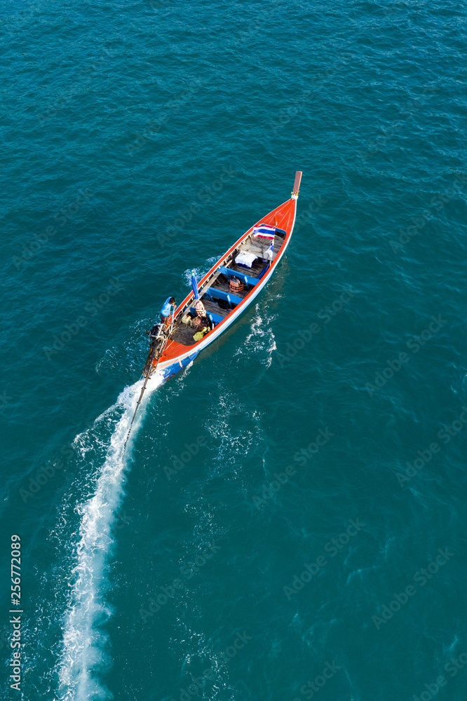 View from above, aerial view of a beautiful long tail boat that sails on a blue sea leaving behind a long wake of water. Phuket, Thailand.