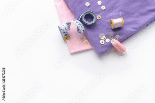 Sewing accessories and fabric on a white background. Fabric  sewing threads  needle  buttons and sewing centimeter. top view  flatlay
