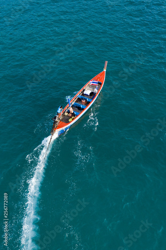 View from above, aerial view of a beautiful long tail boat that sails on a blue sea leaving behind a long wake of water. Phuket, Thailand. © Travel Wild