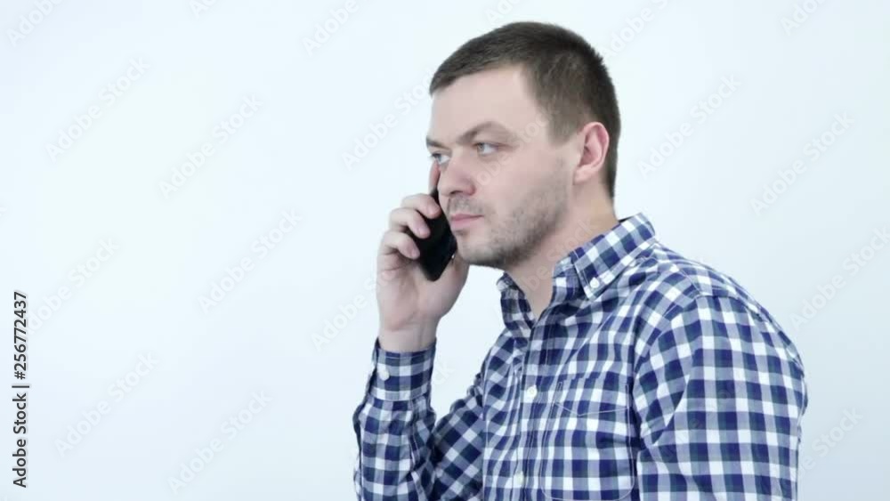 Shocked young man talking on the phone falls smartphone. Sloppy man is missing a smartphone Shocked young man talking on the phone falls smartphone. Sloppy man is missing a smartphone