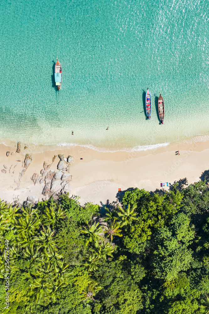 View from above, aerial view of a beautiful tropical beach with white sand and turquoise clear water, long tail boats and people sunbathing, Banana beach, Phuket, Thailand.