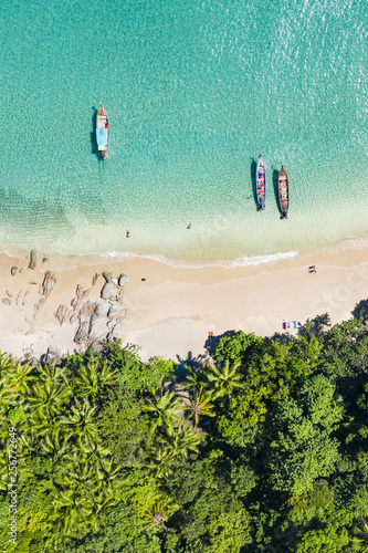 View from above, aerial view of a beautiful tropical beach with white sand and turquoise clear water, long tail boats and people sunbathing, Banana beach, Phuket, Thailand.