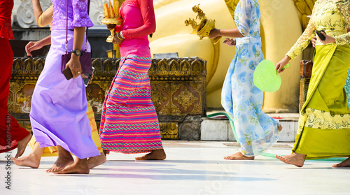 Obraz na płótnie (selective focus) Some Burmese Buddhist faithful are walking barefoot around the Shwedagon Pagoda wearing a traditional and colorful Longyi (traditional Burmese clothes). Yangon, Myanmar. w salonie