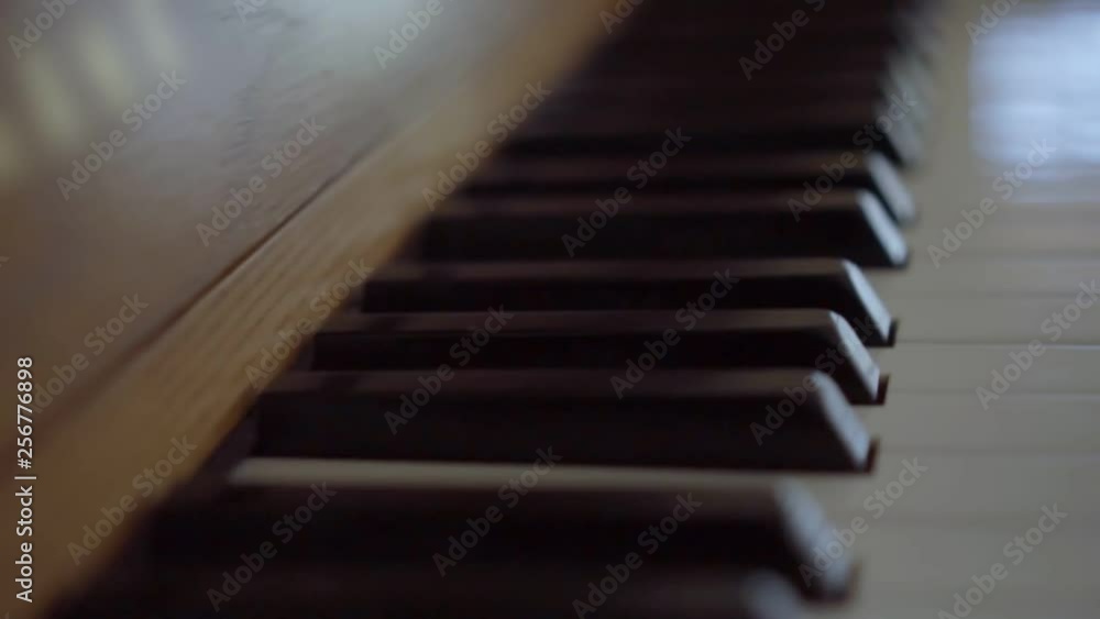 Camera sliding left to right of a wooden stand up piano keyboard with a bokeh effect Camera sliding left to right of a wooden stand up piano keyboard with a bokeh effect