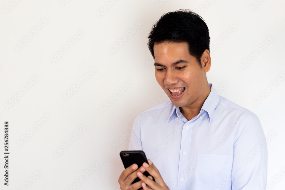 young Asian man looking smartphone with happiness young Asian man looking smartphone with happiness