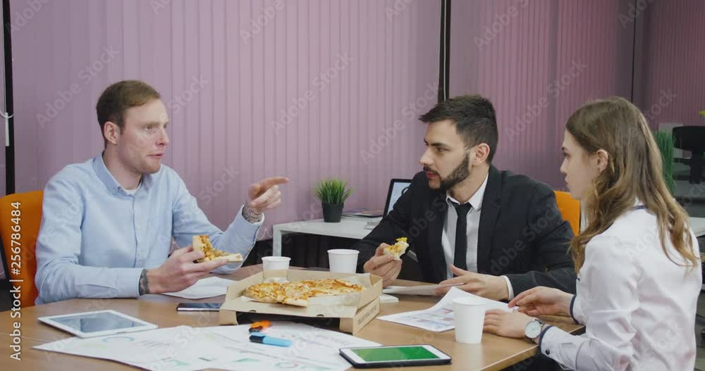 Modern office, office workers at the meeting eat pizza, discuss working information, team buildings. Modern office, office workers at the meeting eat pizza, discuss working information, team buildings.