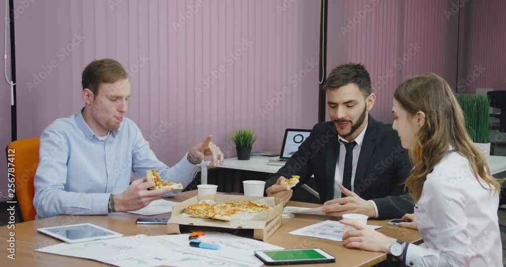 Modern office, office workers at the meeting eat pizza, discuss working information, team buildings. Modern office, office workers at the meeting eat pizza, discuss working information, team buildings.