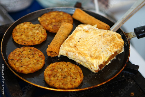 Indian street vendor display bread sandwich,omelette and other items on a frying pan 