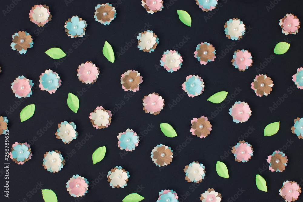 On a black background are many small flowers made of paper. Unusual background for layout. On a black background are many small flowers made of paper. Unusual background for layout.