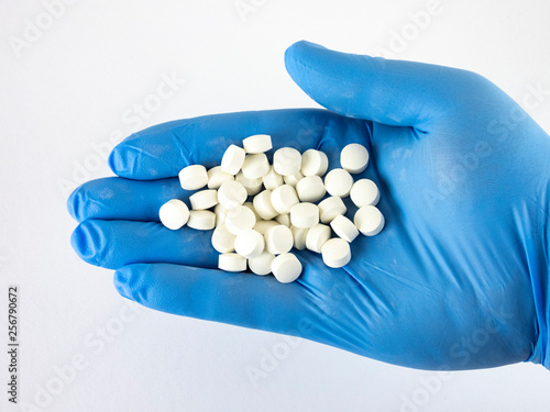 hand in medical glove, hand holds pills, drugs