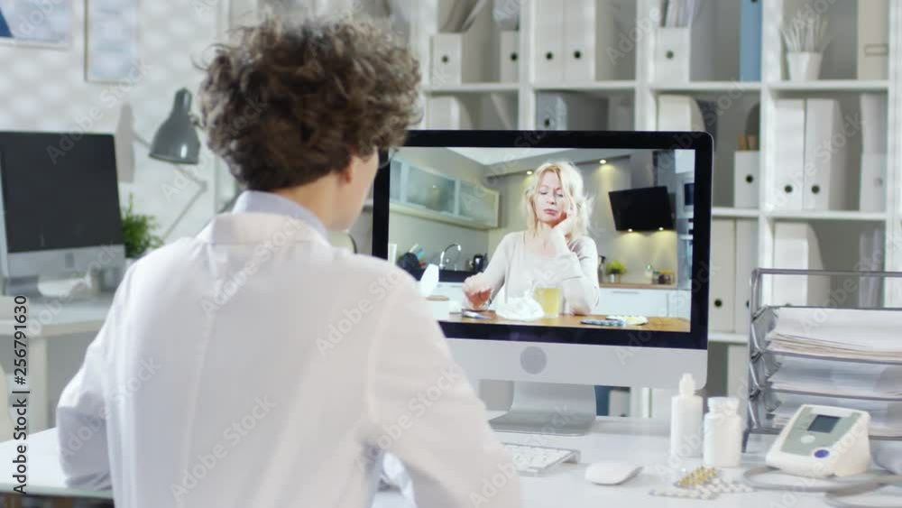 Rare view of female doctor sitting at computer and talking to patient via internet Rare view of female doctor sitting at computer and talking to patient via internet