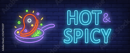 Hot and spicy neon text with frying beef steak on pan