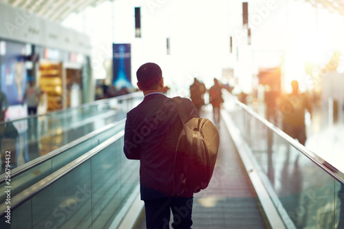 Photography rear view of Asian businessman walking on airport escalator at sunset