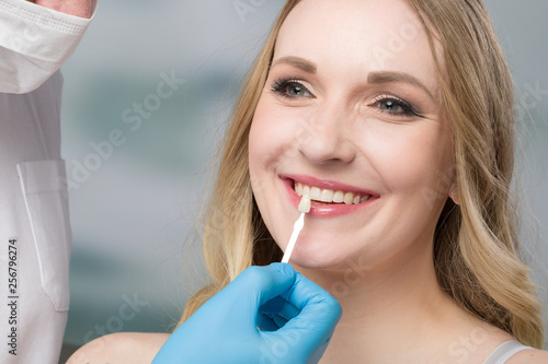 Using shade guide at womans mouth to check veneer of tooth photo