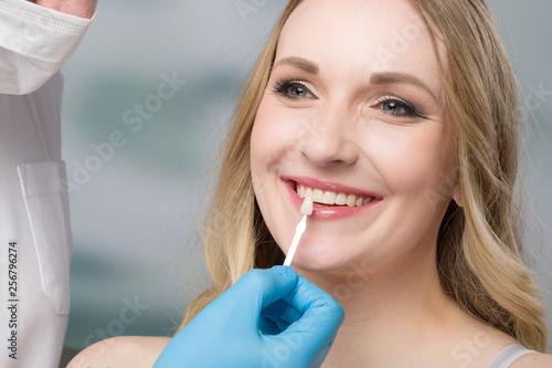 Obraz na płótnie Using shade guide at womans mouth to check veneer of tooth