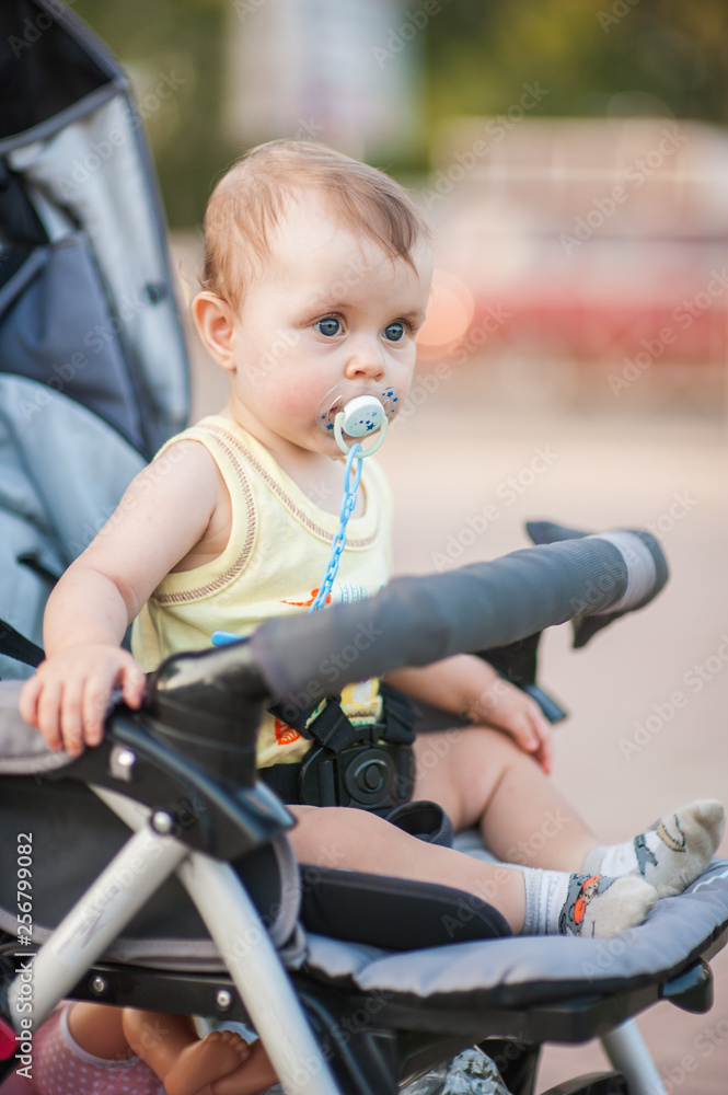 Baby with a dummy in the stroller for a walk Baby with a dummy in the stroller for a walk