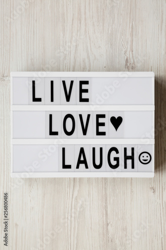 "Live Love Laugh' words on modern board over white wooden surface, top view. Flat lay, overhead, from above.
