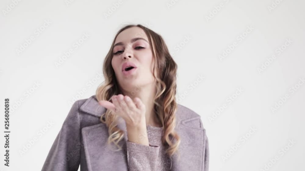 Young beautiful girl in grey coat dancing on white background, slow motion Young beautiful girl in grey coat dancing on white background, slow motion