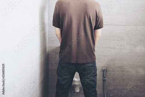 Fototapeta Man is standing pee in a toilet - healthcare urinal concept
