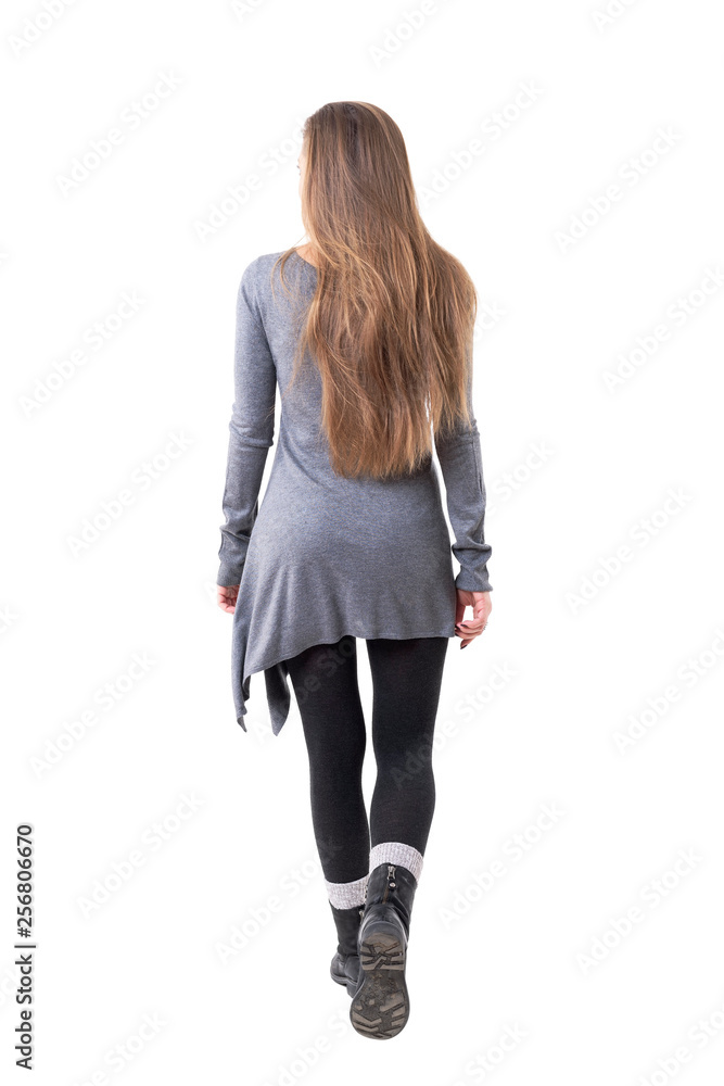 Rear view of casual young stylish woman with long flowing hair leaving ...