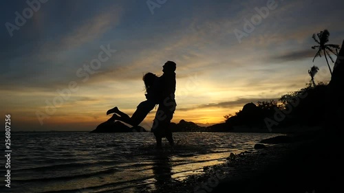 Silhouette of romantic young couple spinning around at amazing sunset, slow motion. 1920x1080
