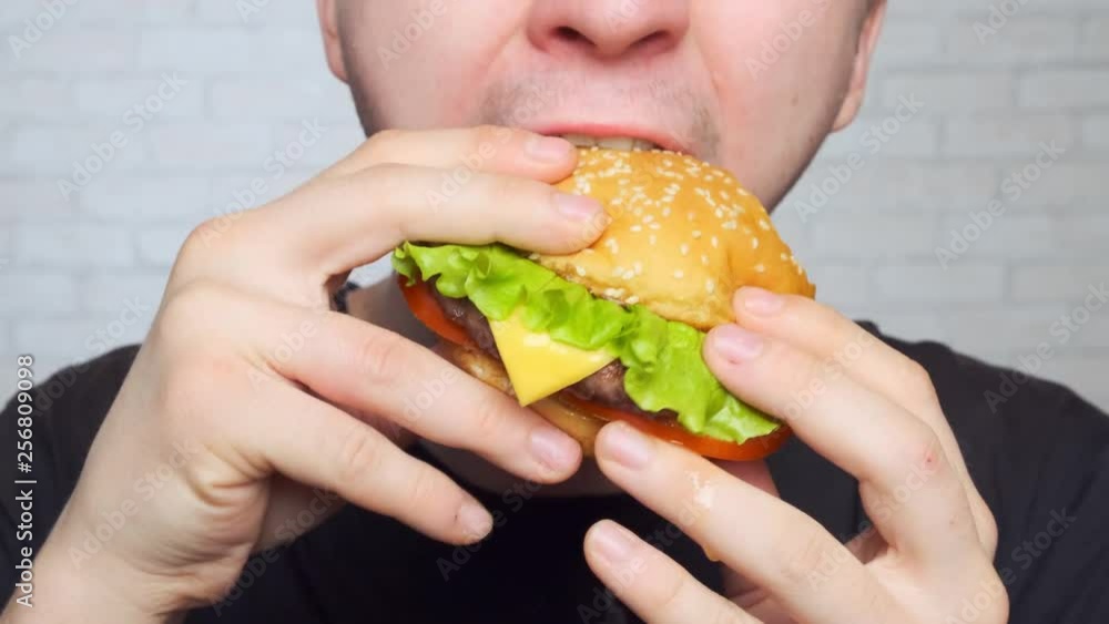 hungry teenager eats junk food. Close-up. Burger, cheeseburger, sandwich. hungry teenager eats junk food. Close-up. Burger, cheeseburger, sandwich.