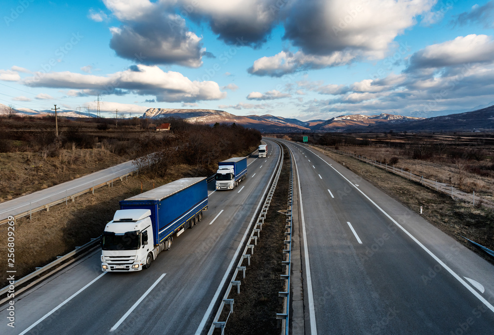 Caravan or convoy of lorry trucks on country highway under a dramatic sky Caravan or convoy of lorry trucks on country highway under a dramatic sky