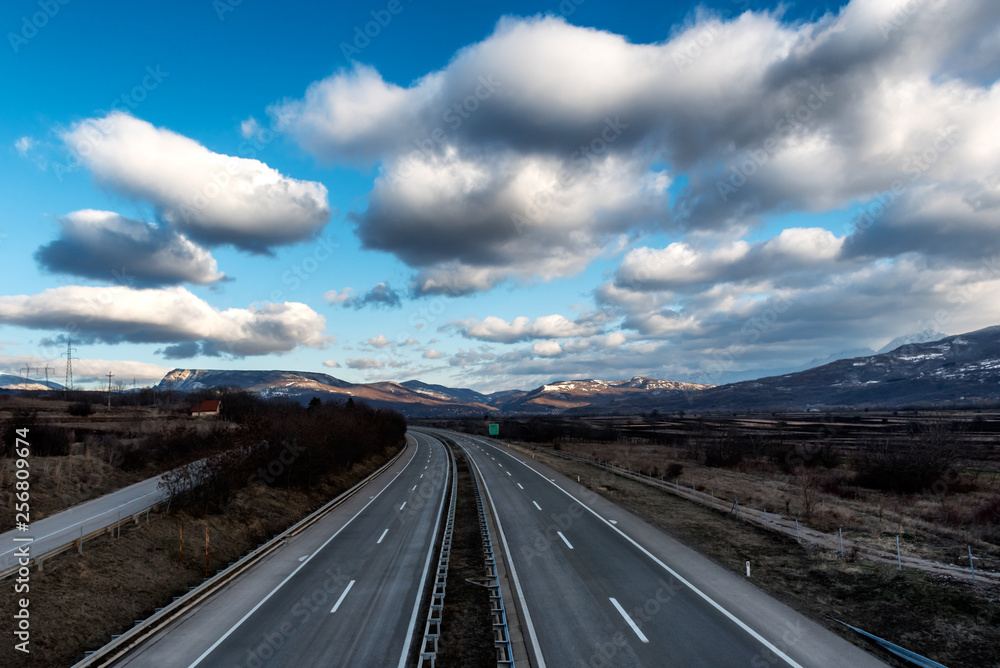 Fototapeta premium Empty freeway or motorway with mountains in the background and with beautiful dramatic sky