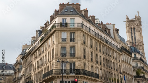 Paris, beautiful building rue de Rivoli, typical parisian facades and windows, with the Saint-Jacques tower in background