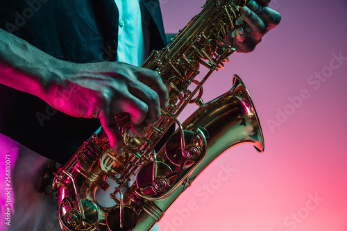 Photography African American handsome jazz musician playing the saxophone in the studio on a neon background